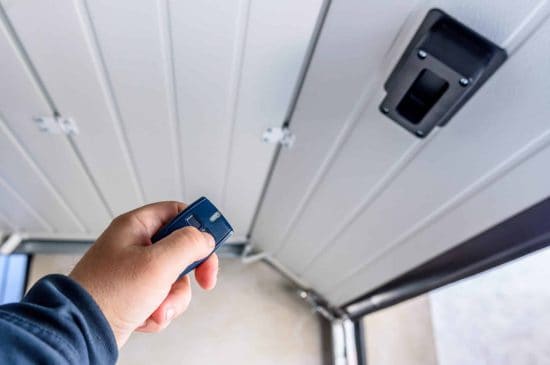 Un homme fermant sa porte de garage ave une télécommande